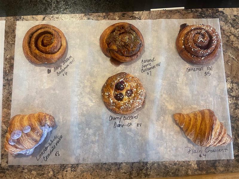 Pastry lineup: cinnamon rolls, cherry custard danish, lavender white chocolate croissant, and a plain croissant